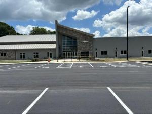 shows freshly paved asphalt parking lot marked with white parking lines and a church in the background